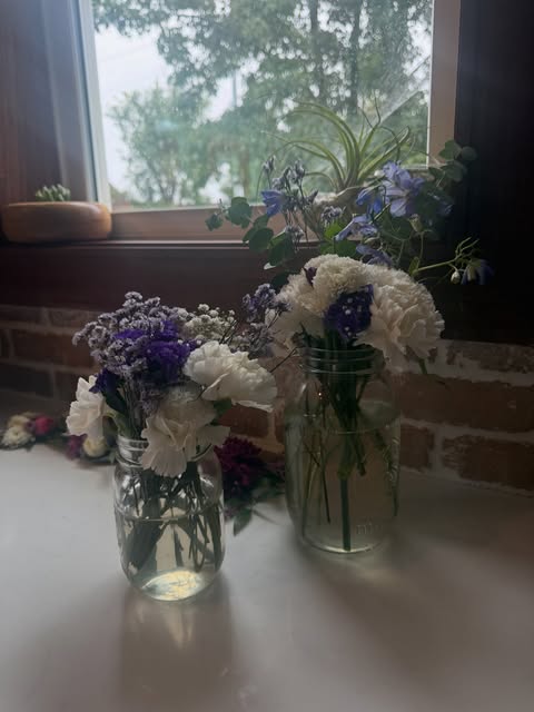 White hydrangeas and delicate purple flowers arranged in glass vases