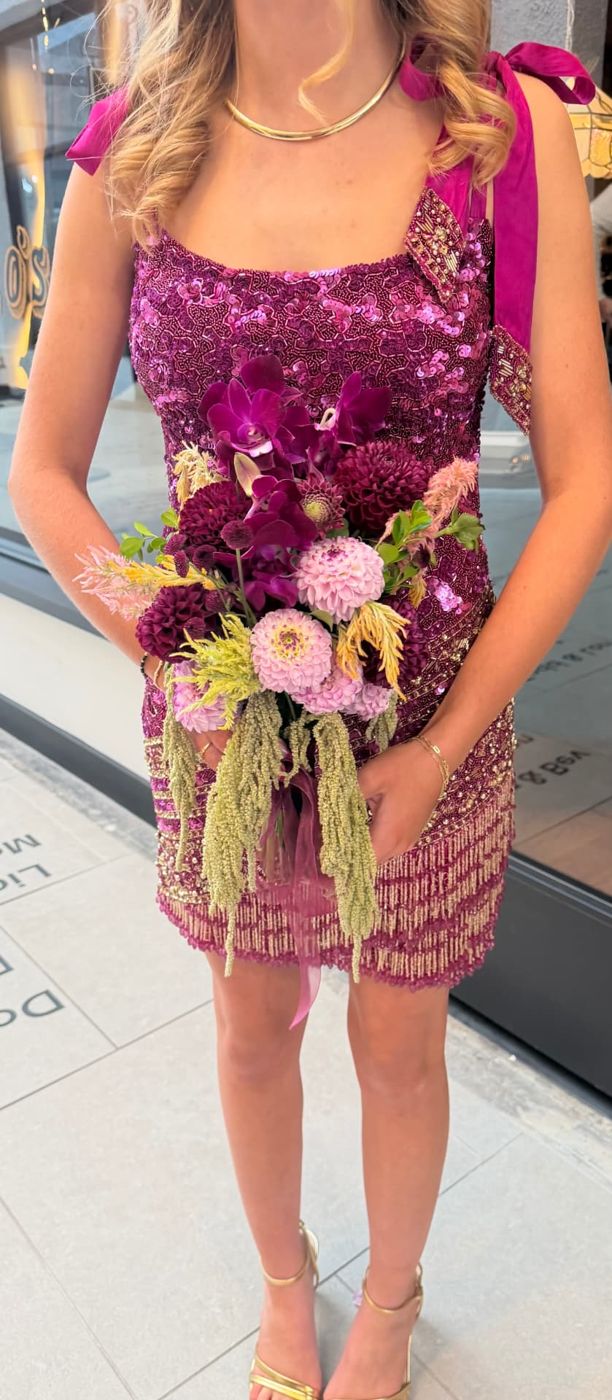 Prom guest in a magenta sequin dress holding a pink and purple bouquet