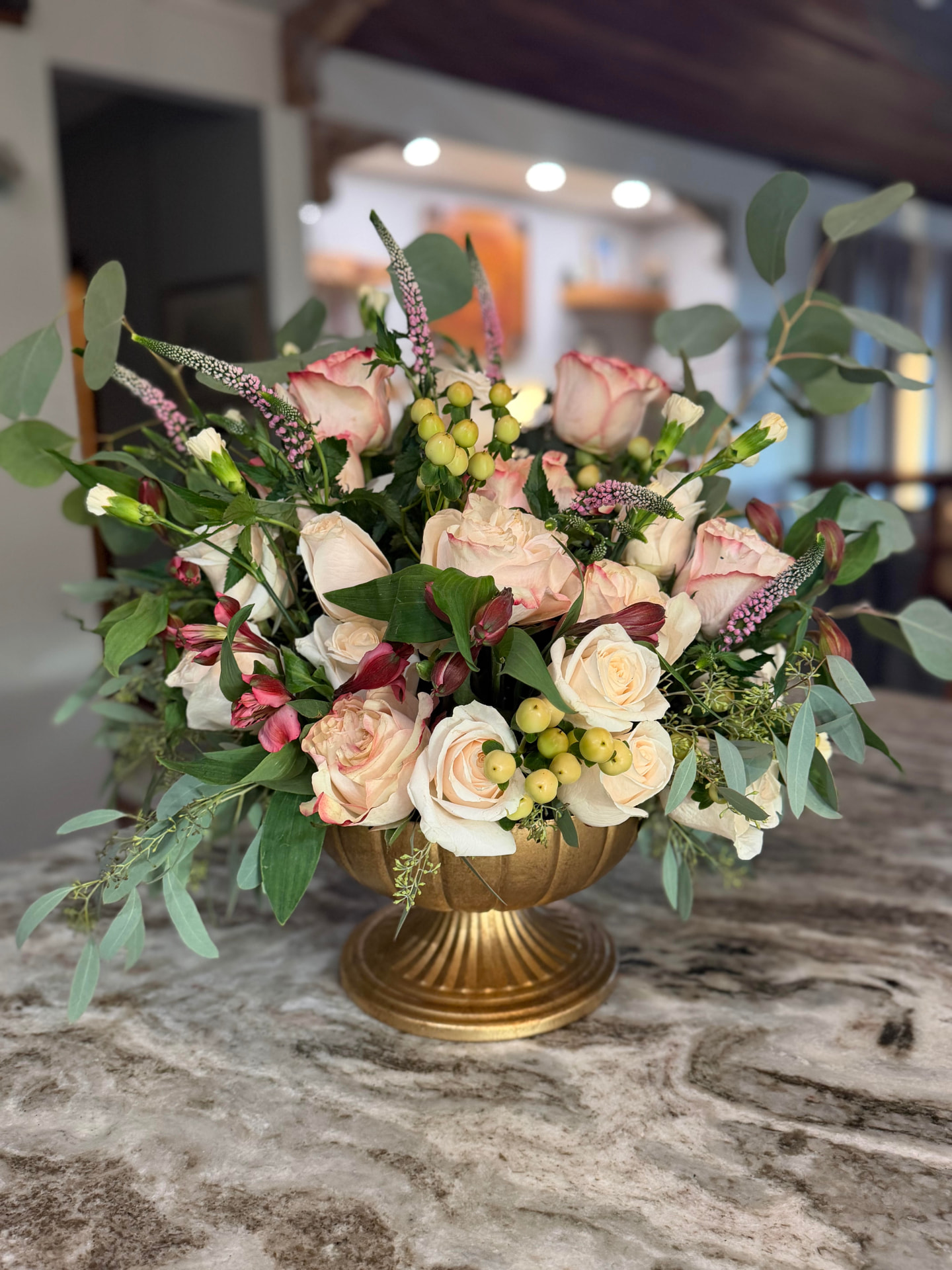 Blush and cream roses with alstroemeria, veronica and eucalyptus in a gold pedestal urn