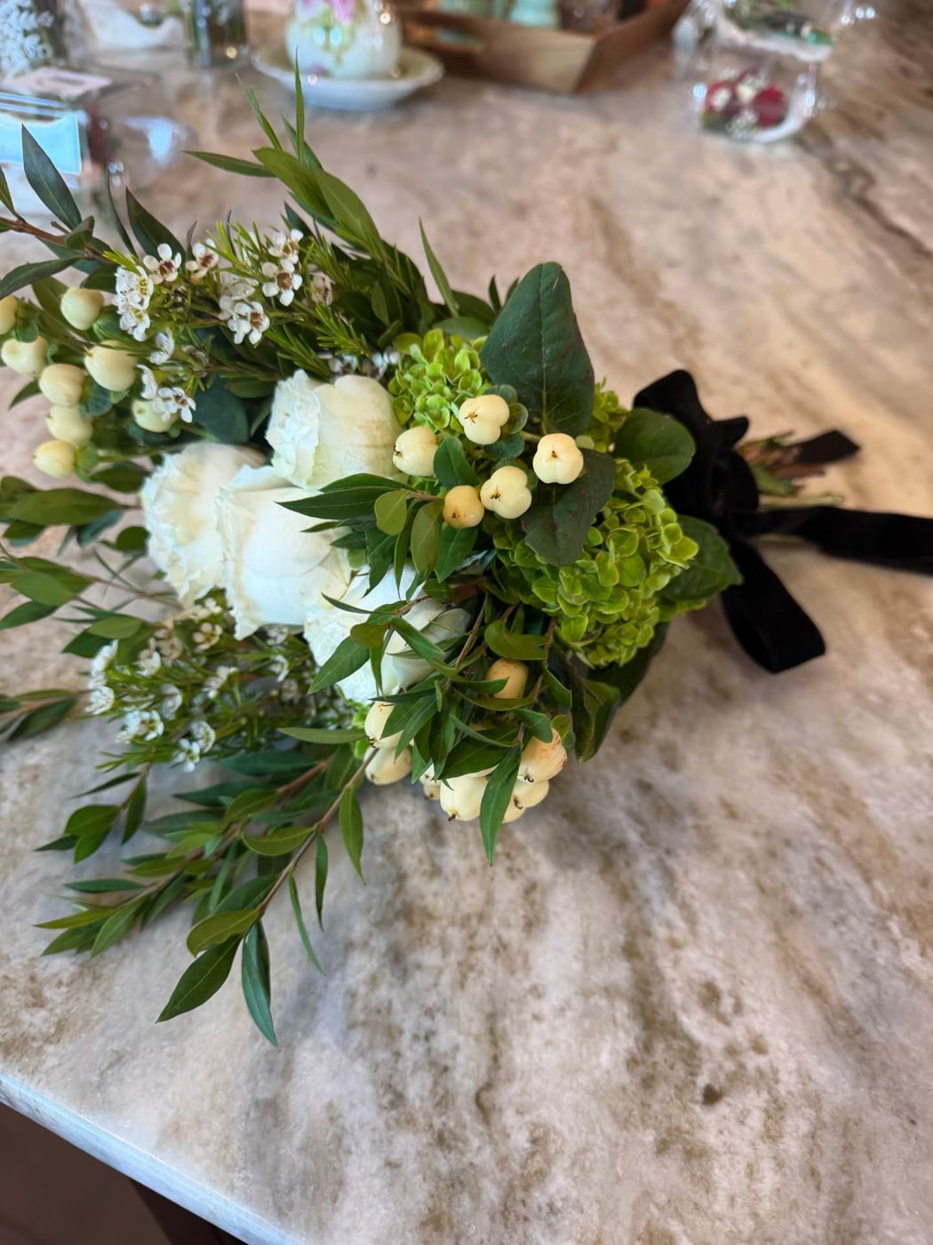 White rose and hypericum berry bouquet with black velvet ribbon on marble