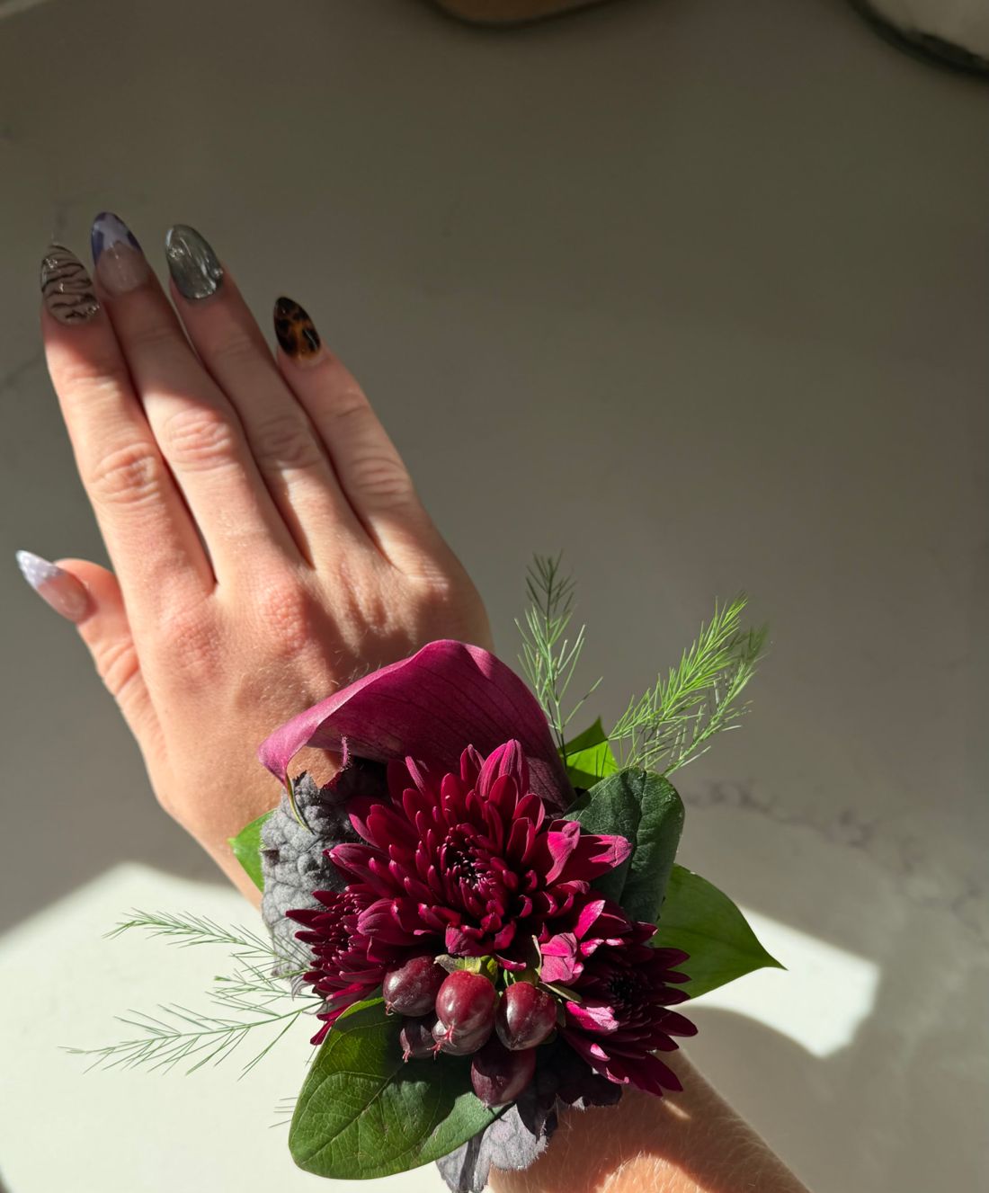 Burgundy dahlia and rose wrist corsage on a hand