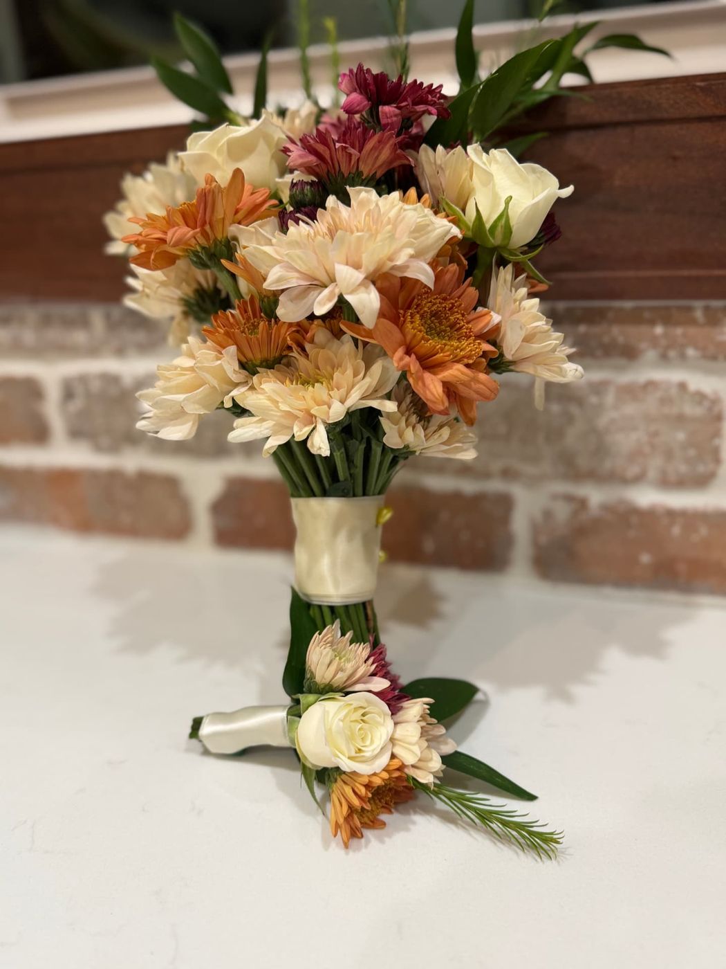 Peach and orange prom bouquet with a matching boutonnière against brick